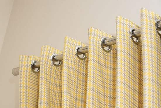 Close-up of yellow checked cotton curtains and their eyelets