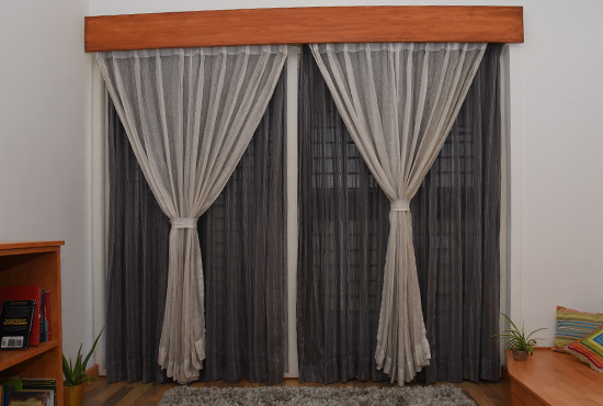 Grey textured blackout curtains with sheers under a pelmet