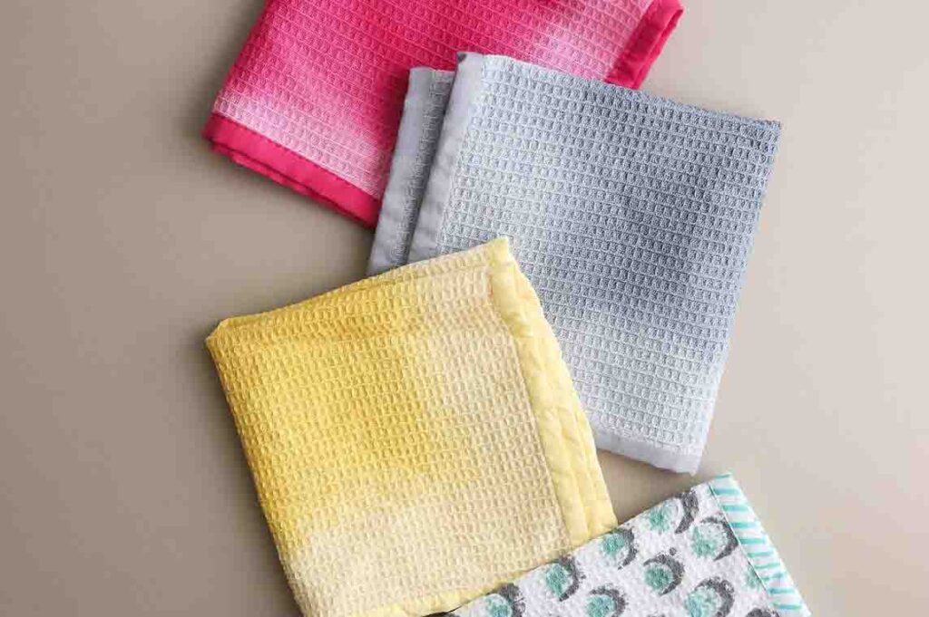 Folded kitchen towels in pink, grey, yellow and blue