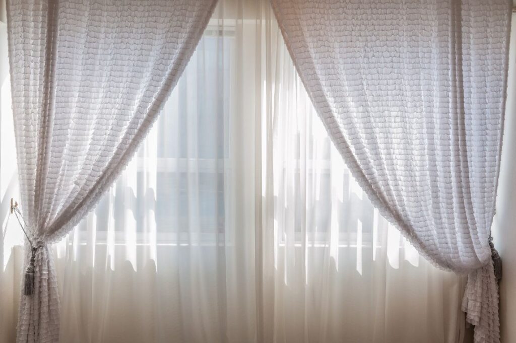 Sheer curtains tied back at a bright window