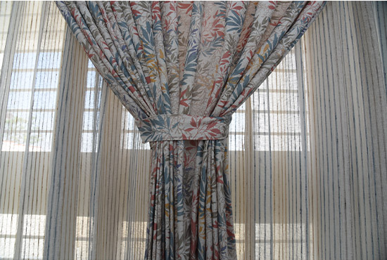 Floral drape gathered with a tie-back over striped sheers